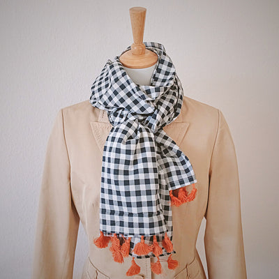 foto-schal-aus-leichter-baumwolle-mit-vichy-karo-schwarz-weiss-und-bommeln-in-orange-aus-fair-trade-an-puppe-mit-blazer-beige