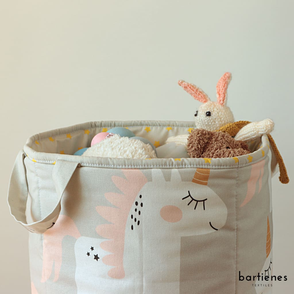 detailfoto-von-aufbewahrung-spielzeugkorb-aus-einhorn-stoff-von-schräg-oben-mit-blick-auf-das-innenleben-aus-stoff-in-beige-mit-neongelben-sternen-gefüllt-mit-kuscheltieren-und-spielzeug