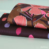 foto-von-zwei-stoffballen-baumwollsatin-mit-den-designs-magnolia-blumen-und-spots-farbkleckse-auf-dark-purple
