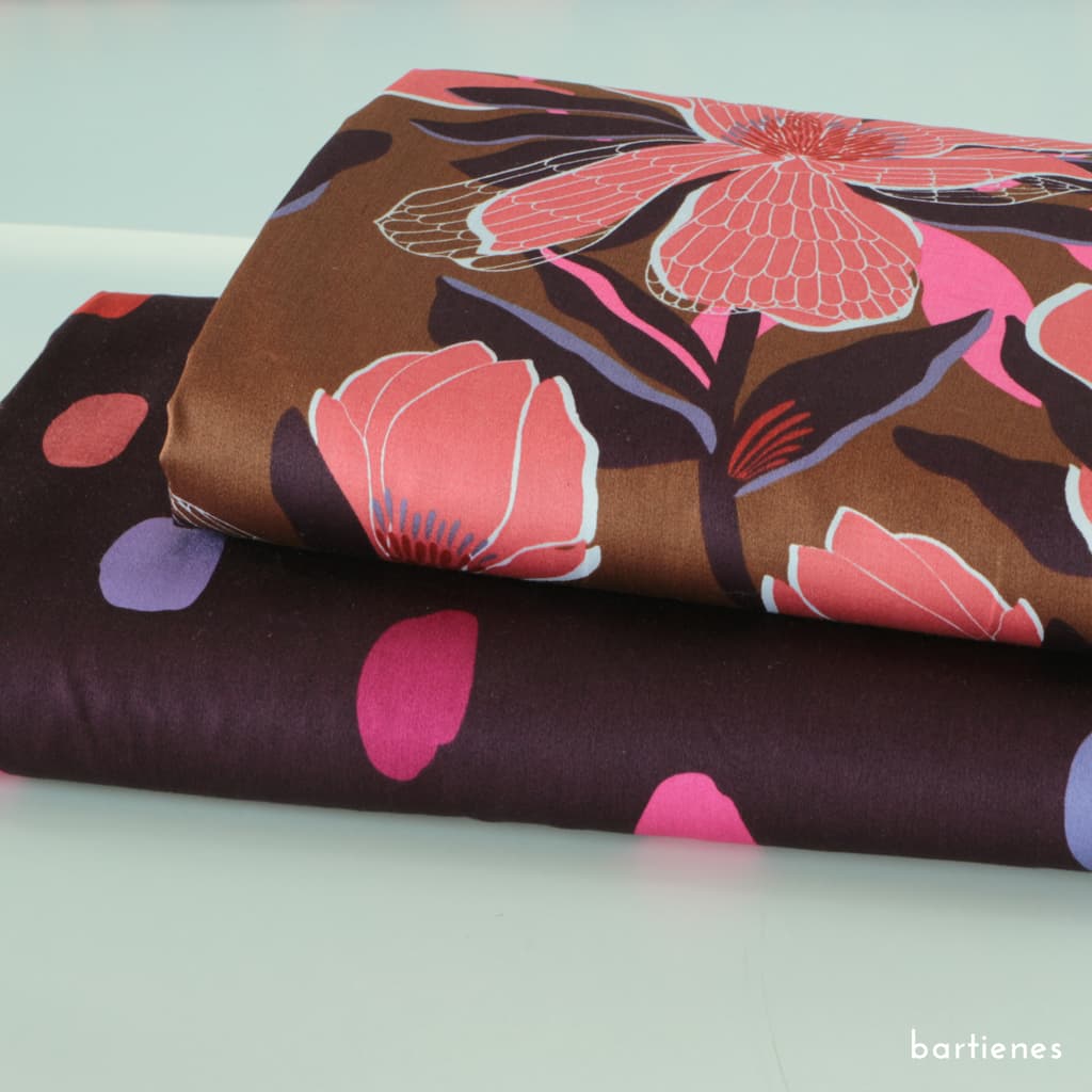 foto-von-zwei-stoffballen-baumwollsatin-mit-den-designs-magnolia-blumen-und-spots-farbkleckse-auf-dark-purple