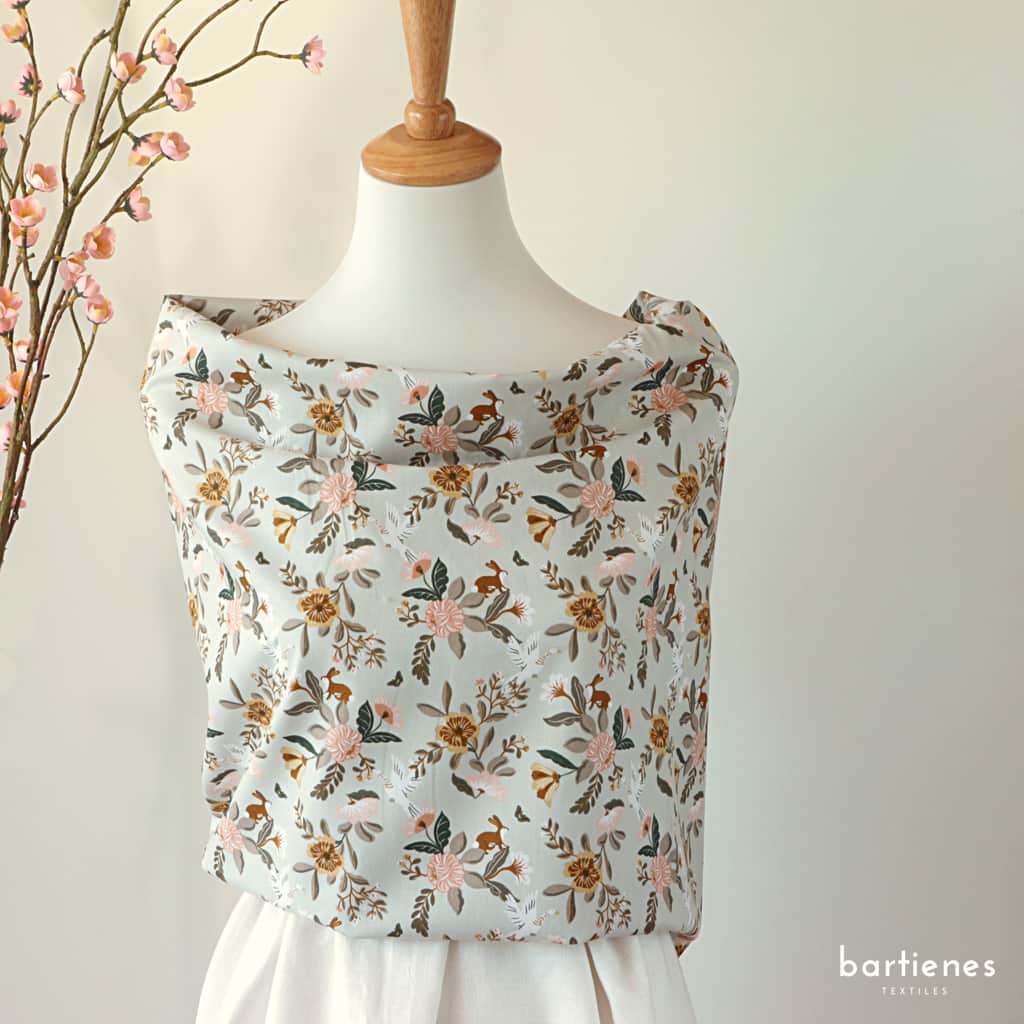 foto-von-bio-popeline-stoff-pastell-grau-grün-blau-mit-blumenbouqets-und-hasen-an-schneiderpuppe-drapiert-wie-bluse-mit-rock-aus-weissem-ramie