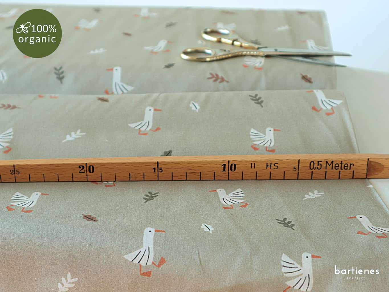 bio-baumwollstoff-kinder-in-zartem-pastell-gruen-mit-muster-aus-kleinen-gaensen-und-blaettern-sowie-schere-und-massstock-fuer-groeßenvergleich