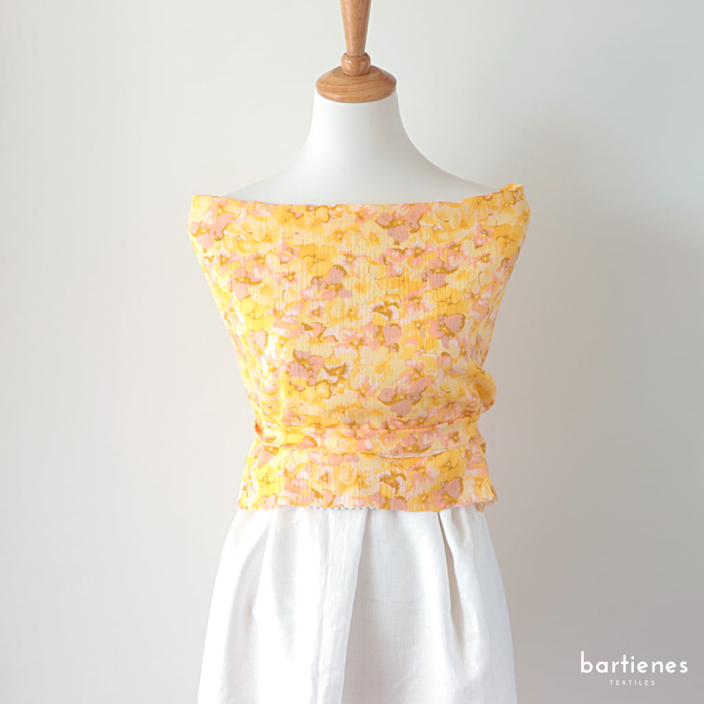 musselin-stoff-in-gelb-mit-blueten-an-einer-schneiderpuppe-als-bluse-drapiert-mit-weissem-leinenrock