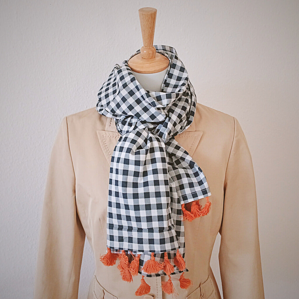 foto-schal-aus-leichter-baumwolle-mit-vichy-karo-schwarz-weiss-und-bommeln-in-orange-aus-fair-trade-an-puppe-mit-blazer-beige