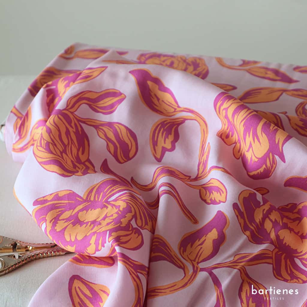 foto-nahaufnahme-von-stoffballen-viskose-stoff-in-flieder-mit-grossen-stilisierten-blumen-in-lila-und-orange