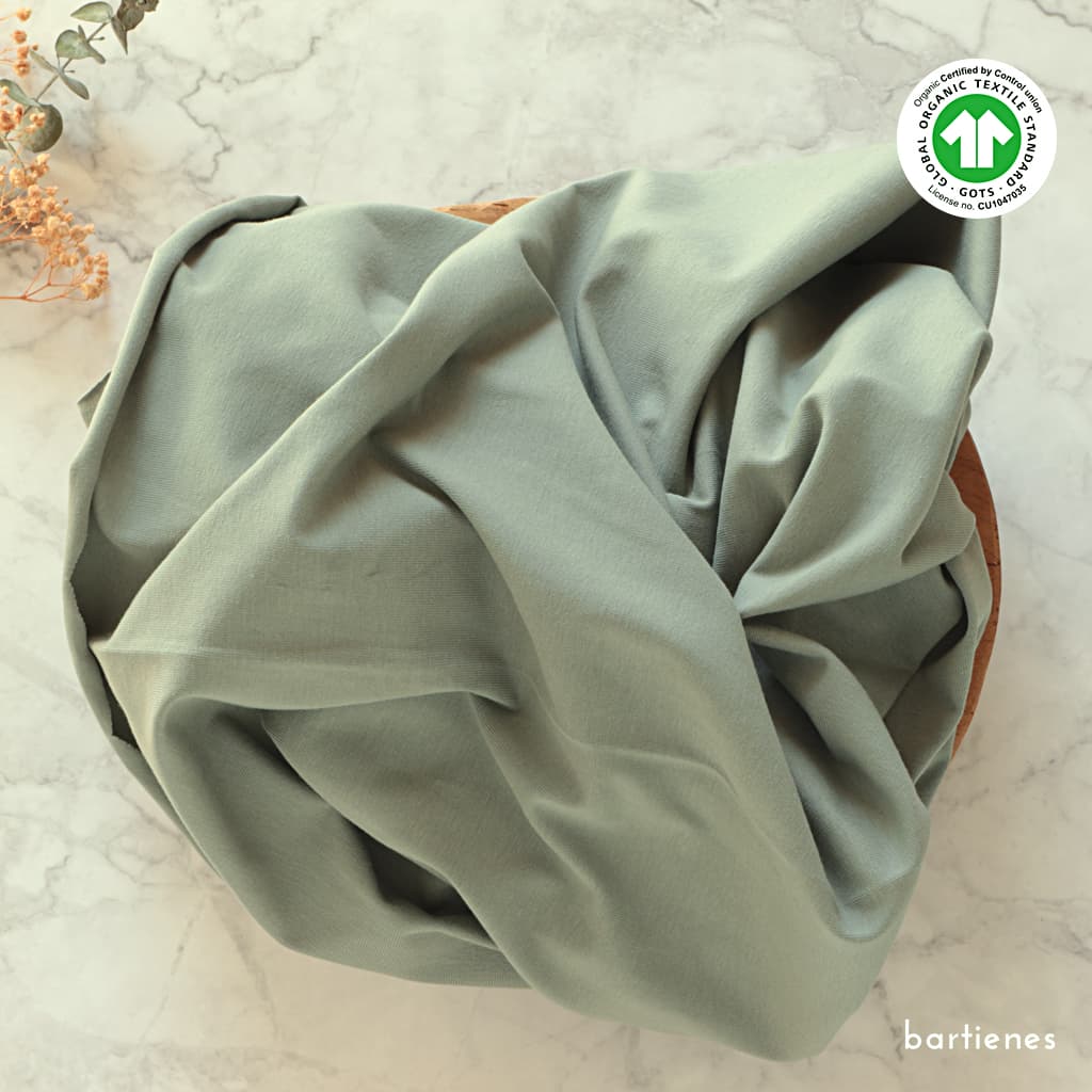 jersey-stoff-aus-bio-baumwolle-in-leuchtendem-koralle-mit-gots-siegel-auf-holztablett