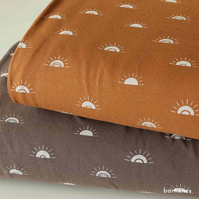 detail-von-zwei-stoffballen-meterware-jersey-in-karamell-und-dusty-brown-jeweils-mit-druck-sunset-in-weiss