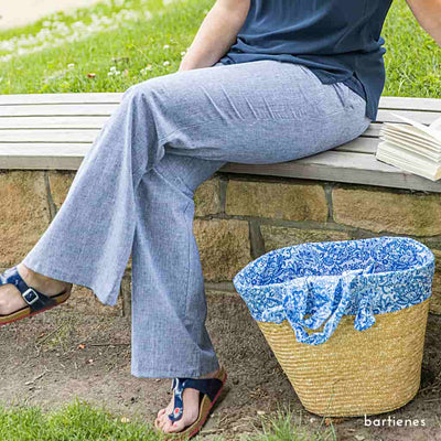 designbeispiel-frau-mit-damen-sommerhose-aus-halbleinen-melange-hellblau-weisse-streifen-sitzend-im-grünen